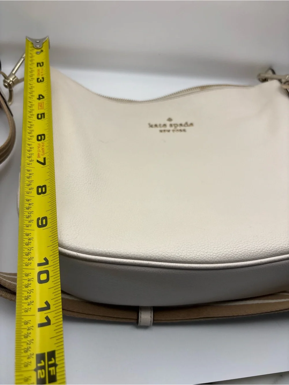 Kate Spade New York cream leather crossbody bag featuring a striped webbing Stra